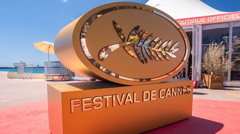 Large golden Palme d'Or sculpture on red carpet with 'Festival de Cannes' text,