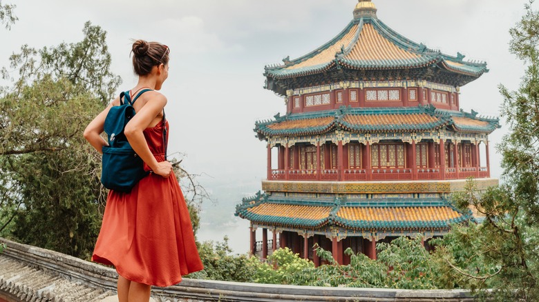 A woman stands looking at a pavilion at the Summer Palace, Beijing