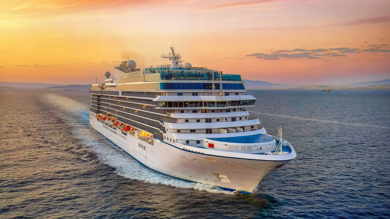 Aerial view of a generic cruise ship traveling over the ocean during golden summer sunset time.