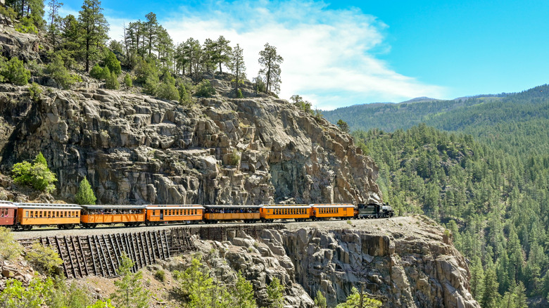 Vintage locomotive snakes around a cliff in the mountains surrounding Durango.