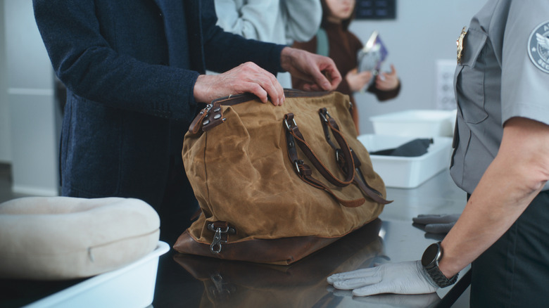 Airport security preparing to check a man's bag