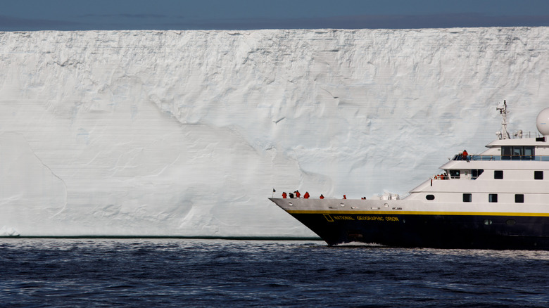 Passengers stand on deck of National Geographic-Lindblad Expeditions ship as it cruises past glaciers in Antarctica.
