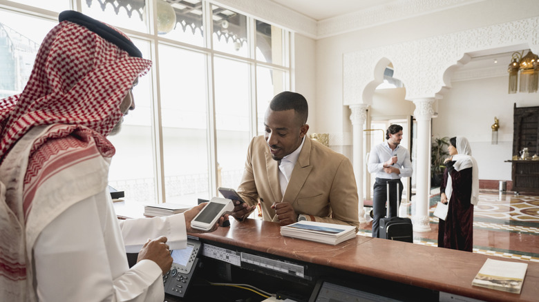 Man paying with a smartphone at a hotel desk