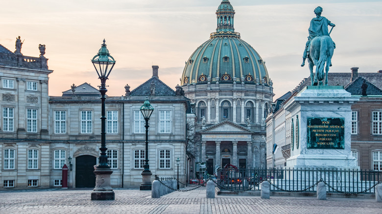 Amalienborg Palace from its square, with large bronze horse statue and the green dome of the Marble Church in the background, at sunrise