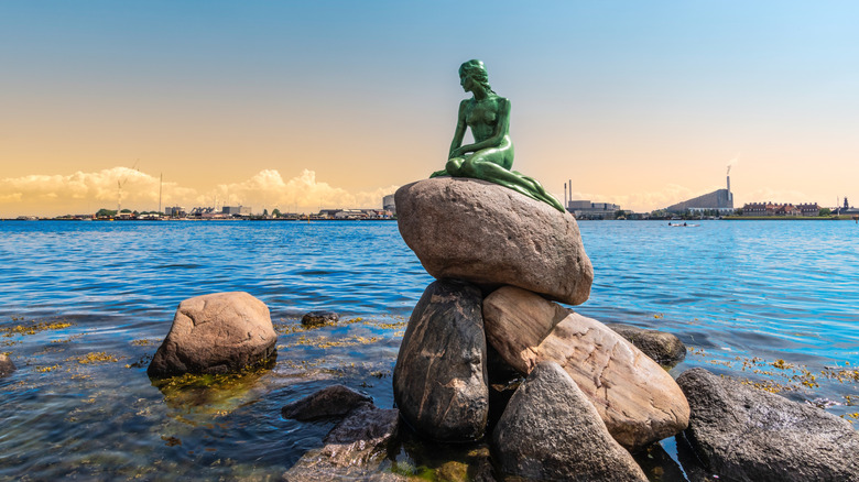 Copenhagen's famous bronze "Little Mermaid" statue sits on a rock in the harbor at sunset