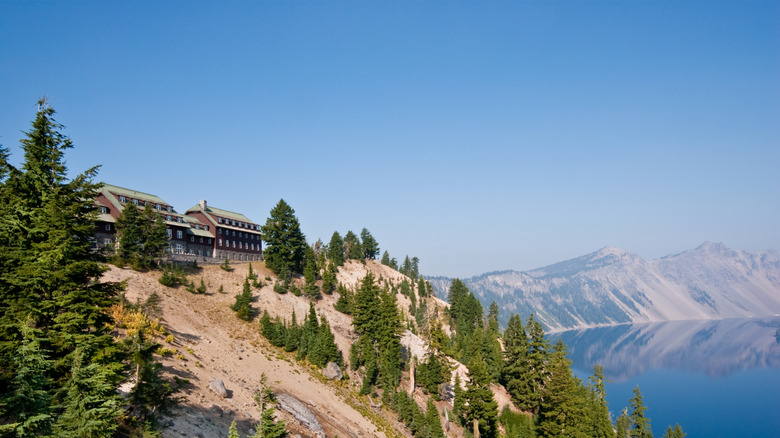 View of Crater Lake Lodge the top of a sloped mountain, with Crater Lake in the background