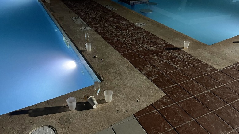 Dirty pool with plastic cups around pool