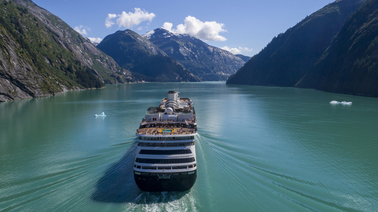 Cruise ship enters Tracy Arm Fjord in Alaska on sunny day.