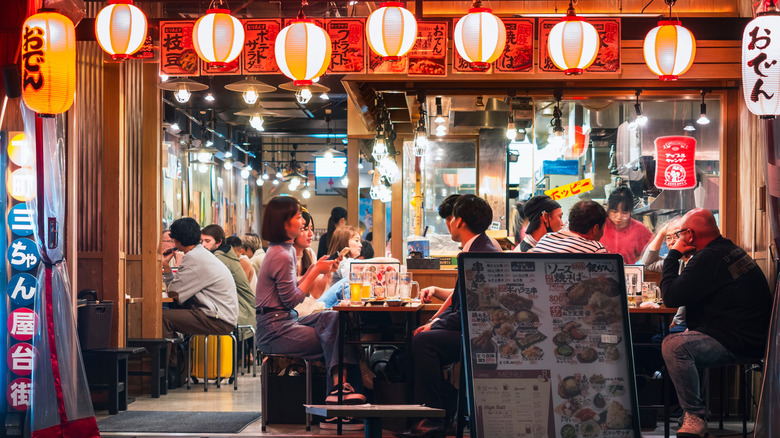 people enjoying food and drinks at a japanese restaurant