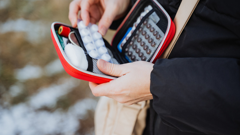 A person removing pills from a shoulder bag