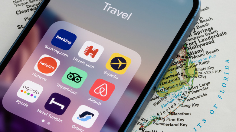 A cell phone laying on top of a map of the U.S. displaying travel app icons.