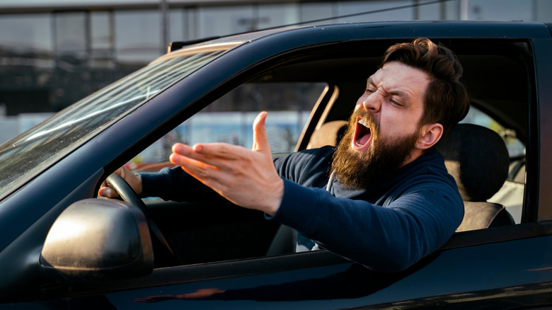 A bearded man shouts from his car