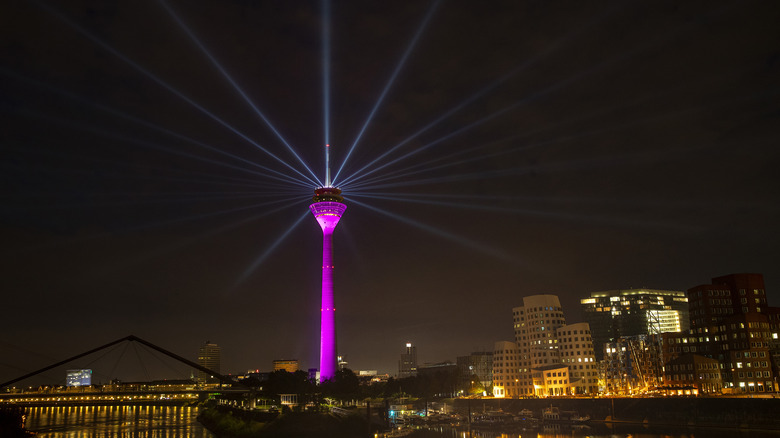 Night view of the Rhine Tower illuminated purple over Dusseldorf