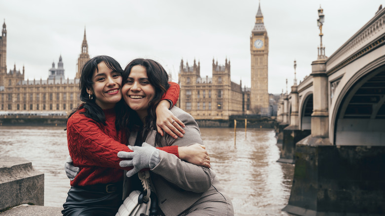 Two young women hugging on the Thames River in London, England