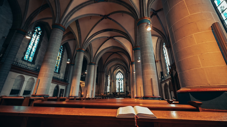 Interior view of Essen Minster's ornate arches and stone walls with a Bible open on a pew in the foreground
