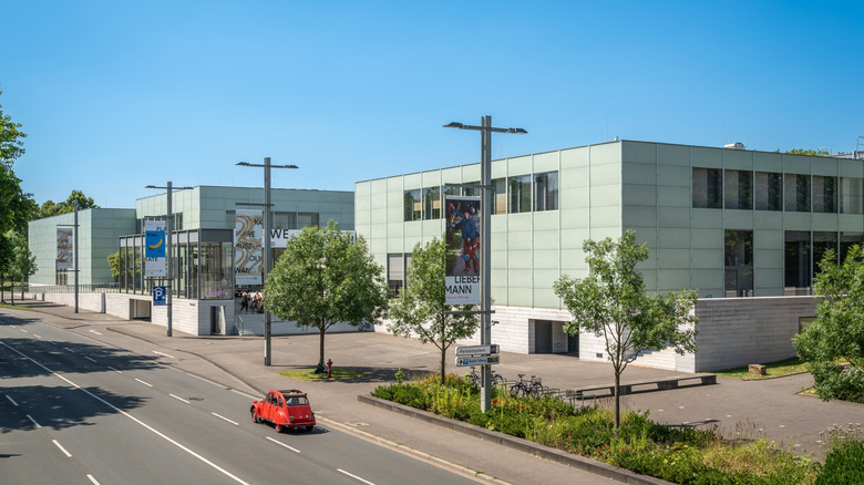 Exterior of the sleek Museum Folkwang on a sunny day with a red Fiat driving by