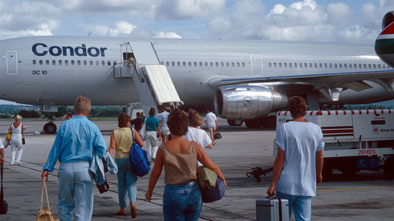 Passengers approach a large Condor plane on the tarmac in the 1980s.