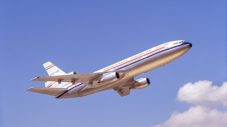 Silver, white, red and blue plane from the 1980s in a blue, partly cloudy sky