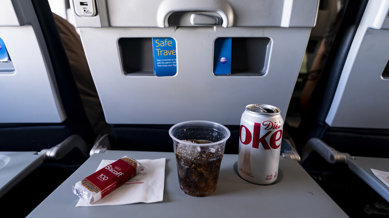 A Diet Coke and a cookie on a plane tray table