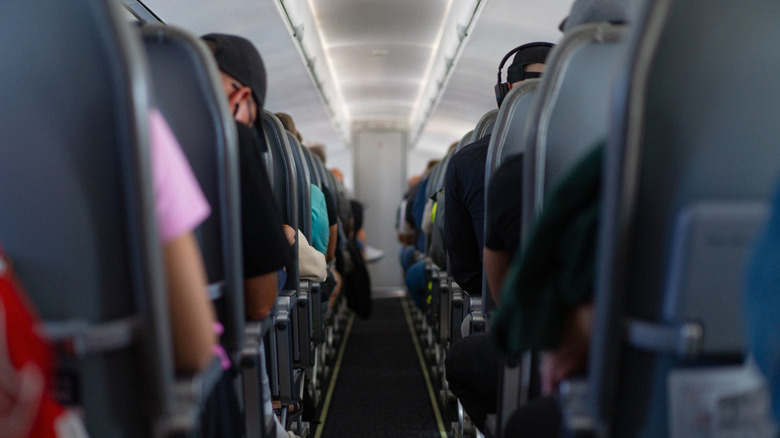 People in their seats on a plane, beside the cabin aisle