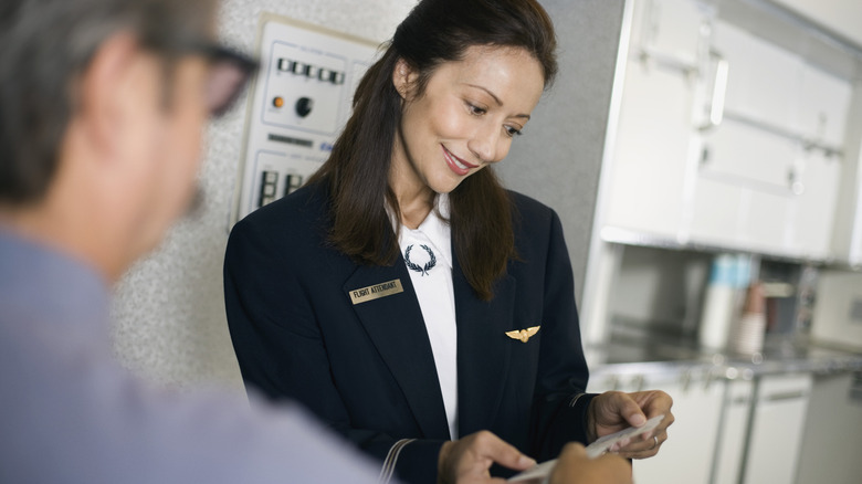 Flight attendant checking a ticket as a passenger enters the plane