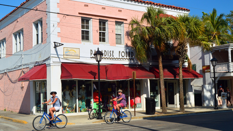 A couple enjoys a bike ride down the street passing stores and boutiques in Key West, Florida