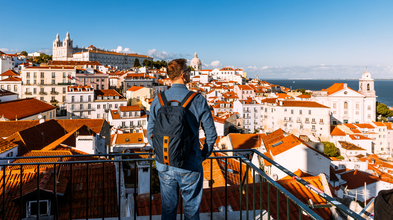 Man wearing a backpack looking over a city from a viewpoint