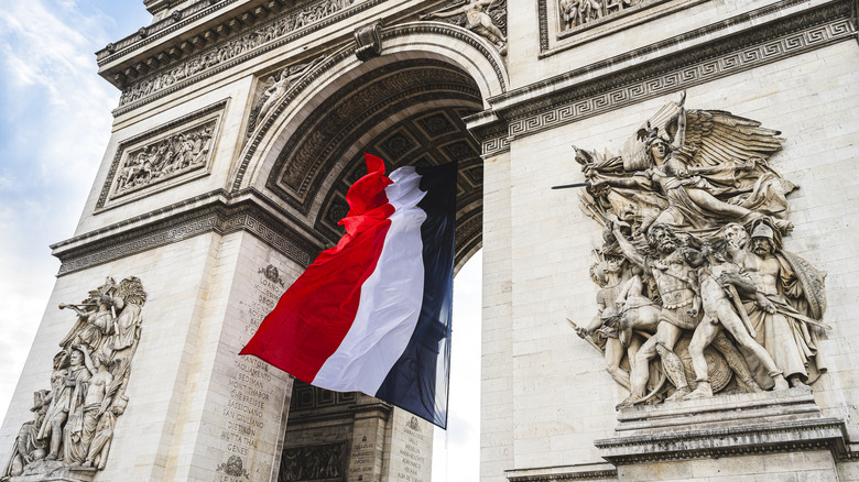 close up shot of the arc's statues with a french flag hanging from its interior
