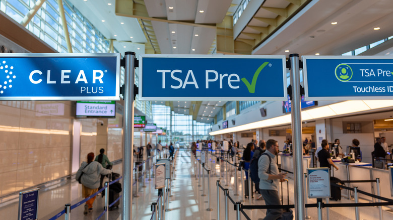 Lanes in a U.S. airport security checkpoint featuring white and blue TSA PreCheck signs.