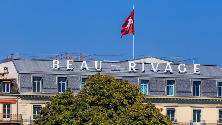 Rooftop signage and Swiss flag on the iconic Beau-Rivage hotel in Geneva