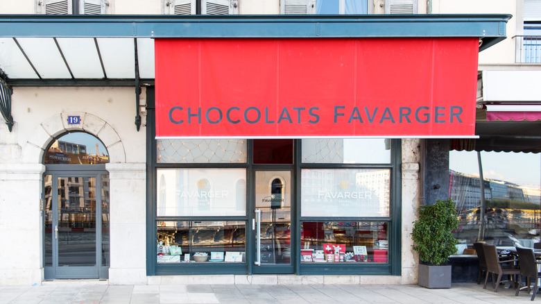 Exterior of Favarger chocolate shop in Geneva, Switzerland with bright red awning and chocolates displayed in the window