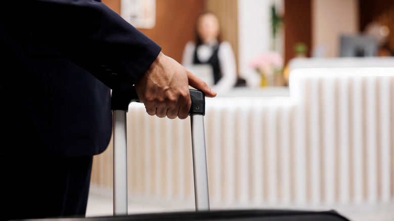 Close-up shot of a suitcase handle as a man arrives in a hotel lobby