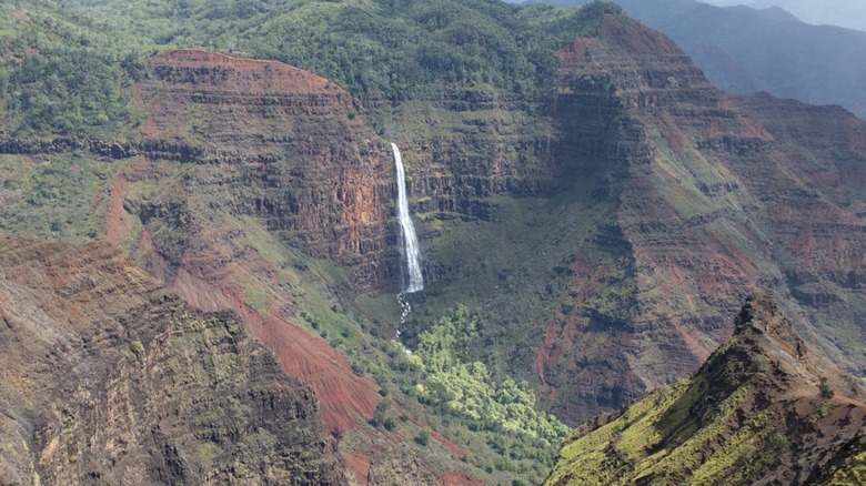 Waipo'o Falls in Waimea Canyon State Park cascading down emerald and copper-colored cliffs