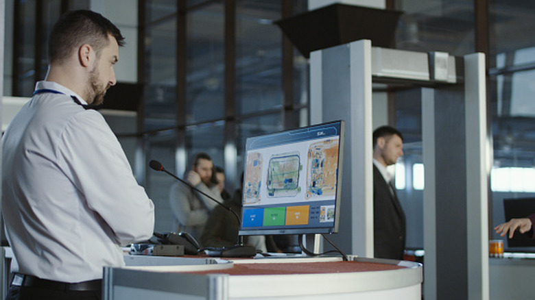 A security agent monitoring a screen with images of luggage.