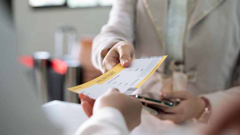 Person receiving a boarding pass by hand from another person