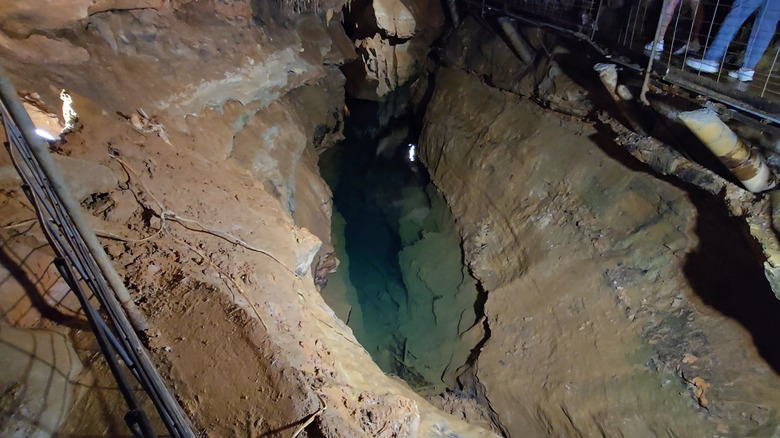 View of bottomless lake with visitors walking on platform above in Cosmic Cavern.