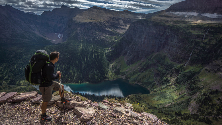 A hiker at the edge of a cliff overlooking Triple Divide Peak