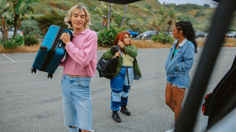 Group of travel friends standing with their luggage close to a car