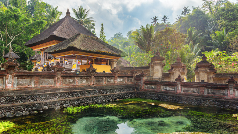 Awesome view of the pond and temple structure at Tirta Empul Temple in Bali, Indonesia with lush foliage in the background