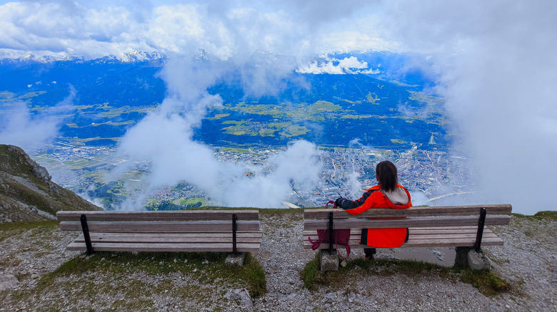 A person sits on a bench, taking in the view of Innsbruck below Nordkette