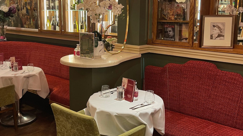 Interior view of Davy Byrnes, Dublin, with red booths, white tablecloths on tables, and a drawing of James Joyce amid other memorabilia on a shelf