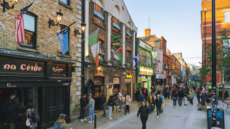 Bustling street in Dublin's Temple Bar district in the daytime with people walking and pubs lining the road
