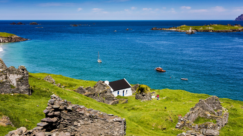 A coastal view with a small white house in front of blue waters in Kerry Seas National Park