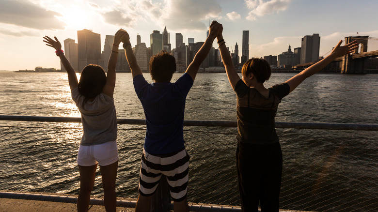 Tourists holding up their hands in front of NYC skyline