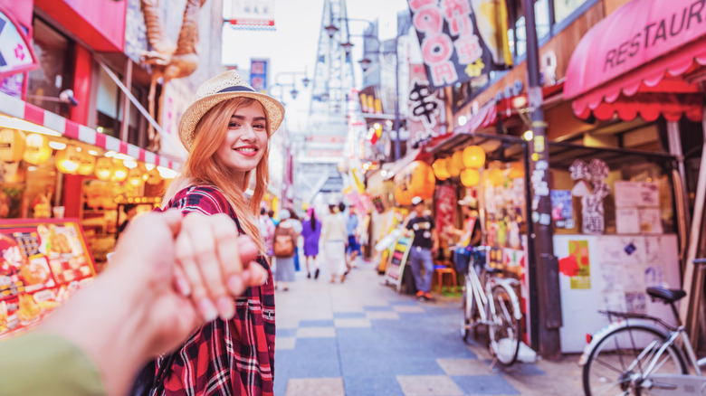 Woman holding a man's hand walking in Japan