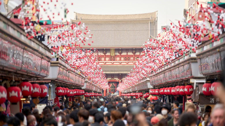 A shopping street leading to Sensoji Temple in Tokyo, Japan, crowded with tourists and lined with red lanterns