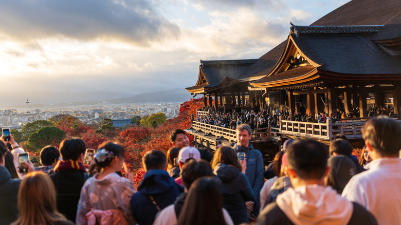 Crowds taking pictures of red leaves during autumn at Kyoto's Kiyomizu-dera Temple, Japan