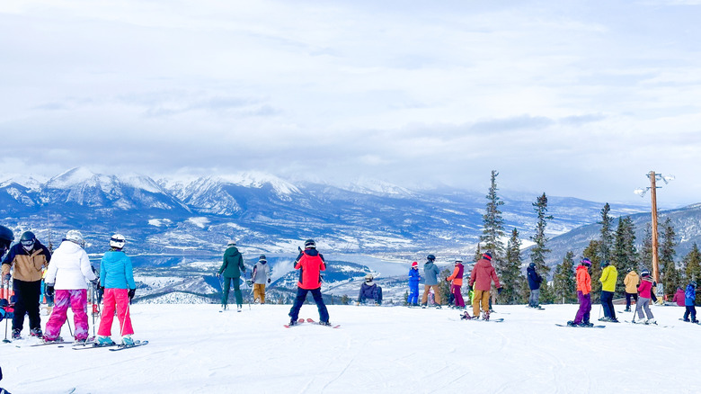 A group of skiers ready to descend the slopes at Keystone, Colorado, with a stunning view of snow-covered mountains in the background.