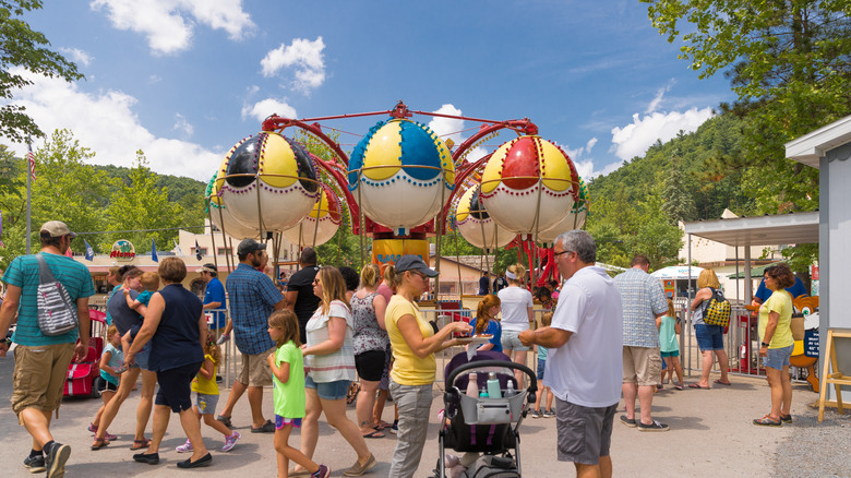 Families wandering on summer day with a kiddie ride in the background at Knoebels Amusement Resort.