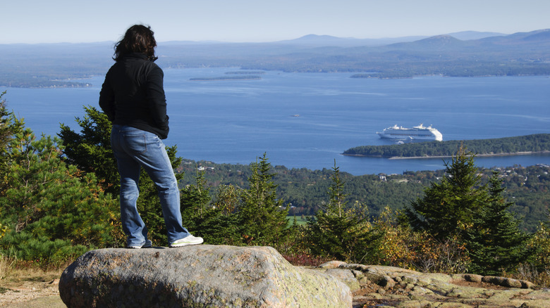 Woman admiring the view of a cruise ship from the top of Cadillac Mountain in Acadia National Park, Maine
